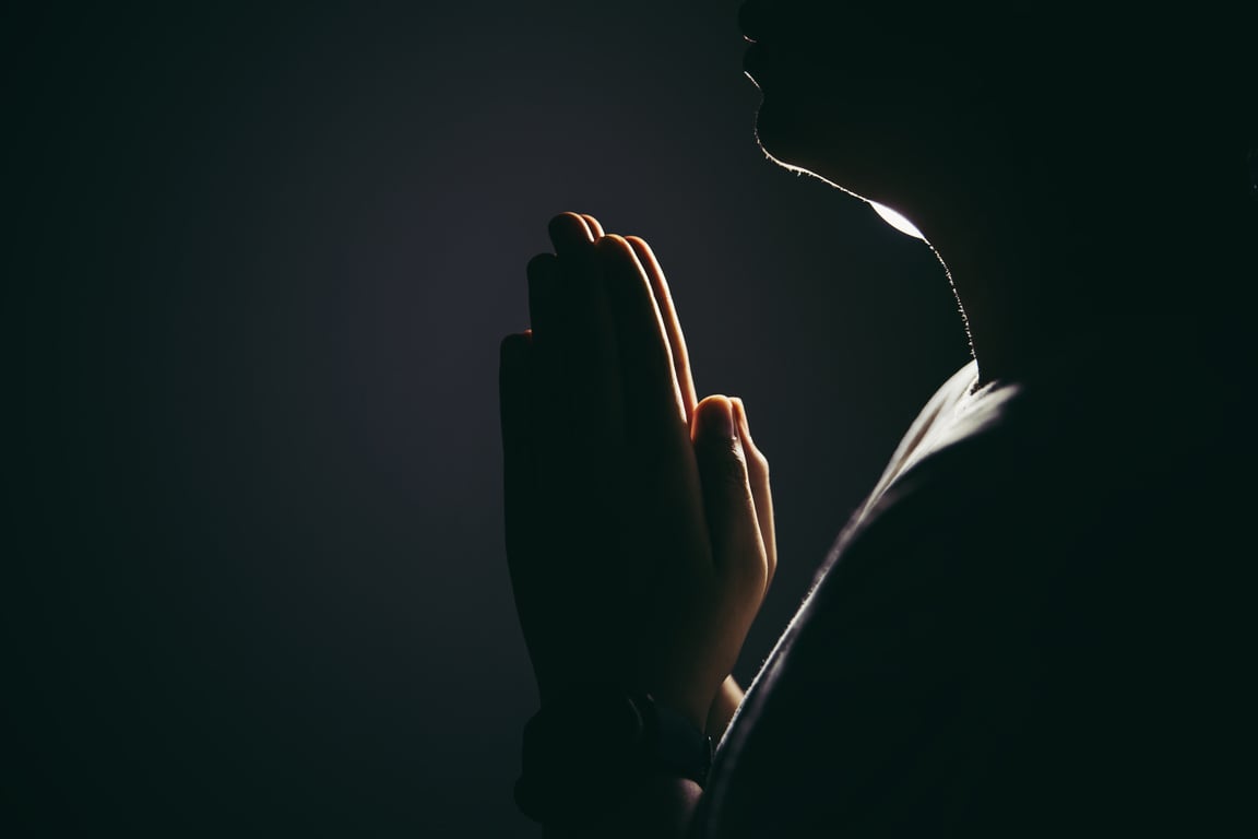 Silhouette of a Person Praying on Dark Background